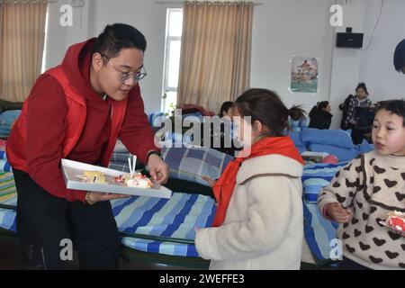 Wushi, regione autonoma cinese di Xinjiang Uygur. 25 gennaio 2024. Un membro dello staff distribuisce torte ai bambini in un sito di reinsediamento nella contea di Wushi, nella regione autonoma Xinjiang Uygur della Cina nord-occidentale, 25 gennaio 2024. I bambini si sono divertiti a condividere le torte di compleanno donate da persone care in un sito di reinsediamento nella contea di Wushi giovedì. Un terremoto di magnitudo 7,1 ha colpito la contea di Wushi nella prefettura di Aksu, nella regione autonoma Xinjiang Uygur della Cina nord-occidentale alle 2:09 di martedì (ora di Pechino), secondo il China Earthquake Networks Center (CENC). Crediti: Gou Lifeng/Xinhua/Alamy Live News Foto Stock