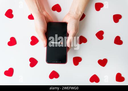 Due mani reggono uno smartphone con cuori rossi su sfondo bianco con l'iscrizione nessun messaggio e un'emoji con cuore spezzato Foto Stock