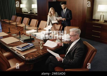 Un gruppo di avvocati birazziali che si occupano di scartoffie affiancate nella classica e spaziosa sala conferenze dell'ufficio Foto Stock