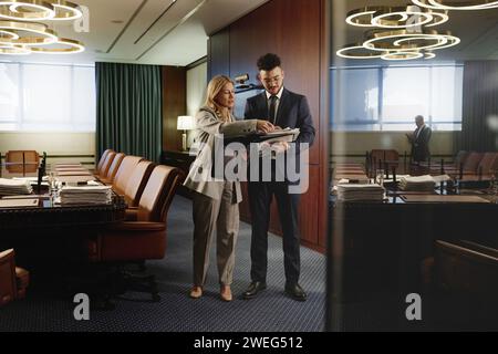 Avvocato donna e il suo giovane collega che esaminano un mucchio di documenti in piedi nella sala conferenze Foto Stock