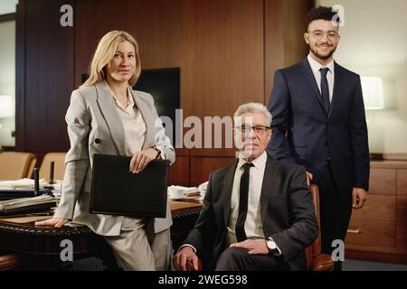 Diversi gruppi di avvocati che si presentano insieme nella sala riunioni dell'ufficio e sorridono alla telecamera Foto Stock