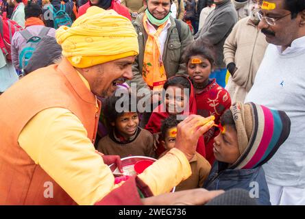 Ai bambini viene dipinto il nome di Lord RAM sulla fronte, alla vigilia della cerimonia di consacrazione del tempio RAM, ad Ayodhya, Uttar Pradesh, India, il 22 gennaio 2024. Foto Stock