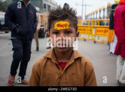 Ai bambini viene dipinto il nome di Lord RAM sulla fronte, alla vigilia della cerimonia di consacrazione del tempio RAM, ad Ayodhya, Uttar Pradesh, India, il 22 gennaio 2024. Foto Stock