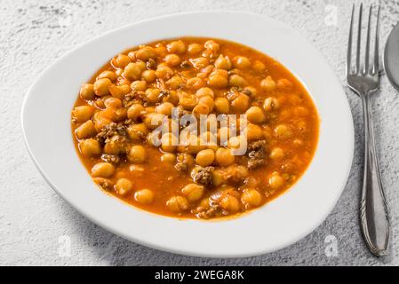 Stufato di ceci con carne macinata su un piatto di porcellana bianca su un tavolo di pietra Foto Stock