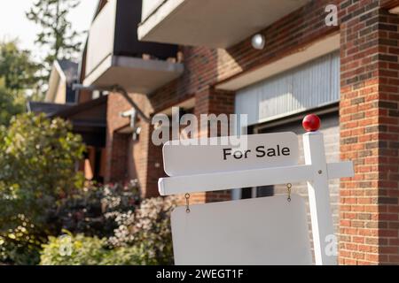 Cartello per la vendita di fronte a una casa in un quartiere residenziale. Spazio di copia per il testo Foto Stock