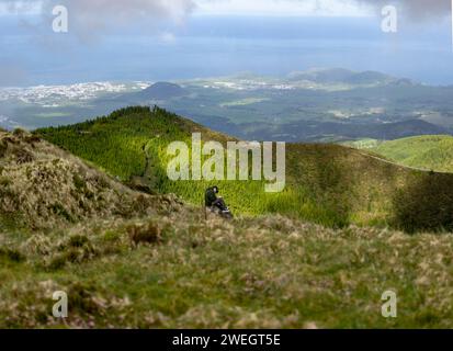 Pittore solitario seduto sulla cima di una montagna a Lagoa do Fogo "Fire Lake" per disegnare il paesaggio. Isola di Sao Miguel nelle Azzorre Foto Stock