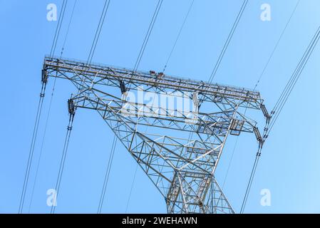 Dettaglio della parte superiore di un alto pilone elettrico ad alta tensione contro il cielo autunnale limpido Foto Stock