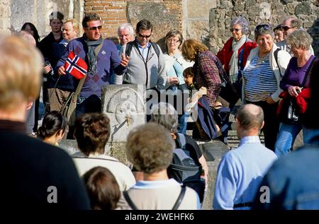 Una guida turistica con una bandiera norvegese parla a un grande gruppo di turisti vicino a un acquario di Pompei, Campania, Italia, Europa Foto Stock