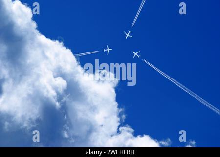 tre aerei con tracce di vapore nel cielo blu volano esattamente l'uno verso l'altro Foto Stock