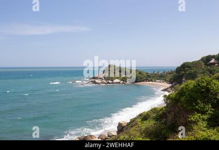 Il paesaggio della spiaggia di Canaveral con montagne rocciose e mare blu caraibico in giornata di sole al parco nazionale di Tayrona Foto Stock