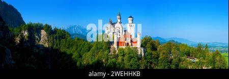 panorama del castello di neuschwanstein in una foresta verde con cielo blu al sole, Füssen, Baviera, Germania Foto Stock
