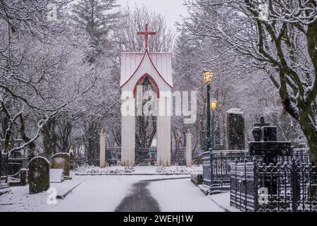 Neve che cade nello storico cimitero di Hólavallagarður a Reykjavik, Islanda Foto Stock