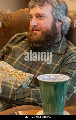 uomo caucasico adulto di 35 anni con baffi e barba marrone riccia che diventa prematuramente grigio sulla testa. Primo piano, sorridendo. Foto Stock