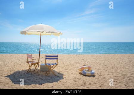 Sdraio e ombrellone perfettamente posizionati su una spiaggia tranquilla invitano al relax, catturando l'essenza della serenità del mare e la promessa di una tranquilla esca Foto Stock