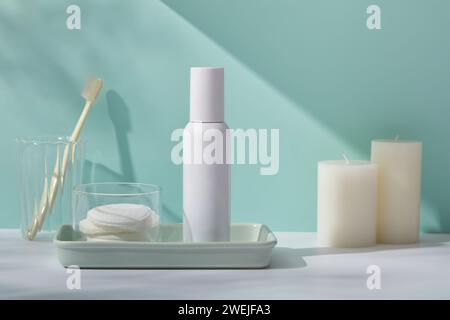 Scenario di mockup per prodotti cosmetici con flacone di plastica senza etichetta e rimozione del cotone da trucco su vassoio rettangolare, spazzolini in tazza di vetro e profumati Foto Stock