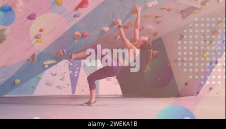 Forme colorate astratte contro l'arrampicata su muro di donna caucasica in palestra Foto Stock