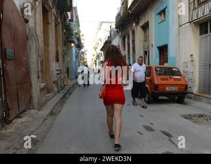 Una donna cubana che cammina a bordo di una vecchia Fiat 126 polacca a l'Avana vecchia, Cuba. Foto Stock