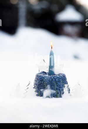 Scultura invernale di ghiaccio all'aperto con fiori di Giacinto d'uva congelati, stella di cristallo, albero di Natale, pupazzi di neve e candela blu sulla neve. Foto Stock