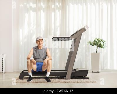 Un anziano seduto su un tapis roulant a casa Foto Stock