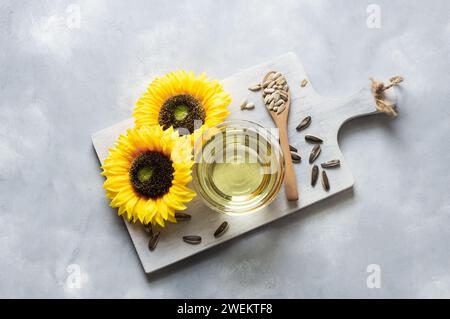 Bottiglia di olio di semi di girasole con fiori su fondo rustico, olio da cucina, helianthus annuus Foto Stock