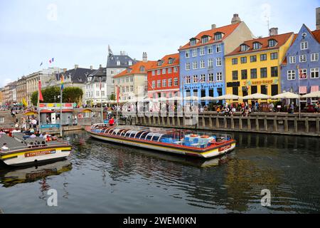 Copenaghen, Danimarca - 17 agosto 2023: Il canale di Nyhavn. I turisti navigano in barca a bordo del fiume Nyhavn con bar e ristoranti a buildi Foto Stock