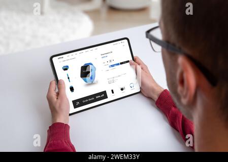 Un ragazzo acquista uno smartwatch online su una moderna pagina Web di e-commerce. Tecnologia alla ricerca dei più recenti gadget indossabili Foto Stock