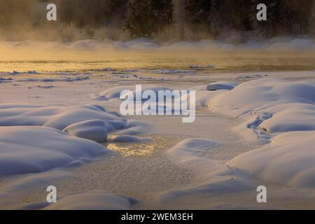 Fiume mezzo ghiacciato, dove il vento ha contribuito a creare bellissime piccole colline sul ghiaccio, rilasciando la nebbia quando viene riscaldata dall'alba Foto Stock