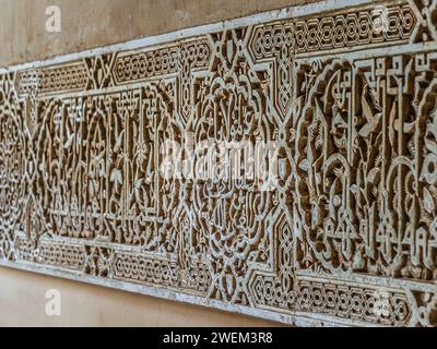 Alhambra a Granada, Spagna, Andalusia. Dettaglio di un muro di pietra scolpita di 800 anni in stile islamico, motivo floreale, iscrizione Foto Stock