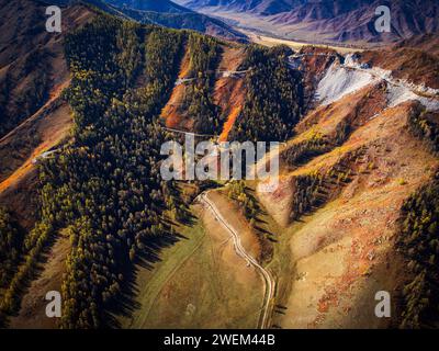 Scatto aereo mozzafiato che cattura i vivaci colori autunnali e il terreno accidentato del paesaggio delle montagne Altai. Foto Stock
