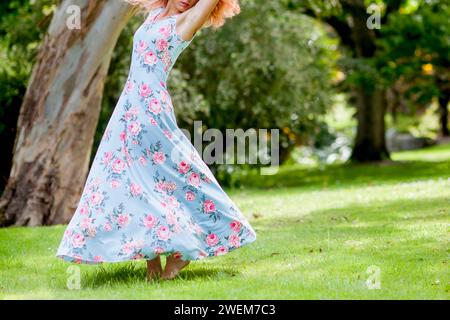 Donna in abito floreale Dancing in giardino Foto Stock