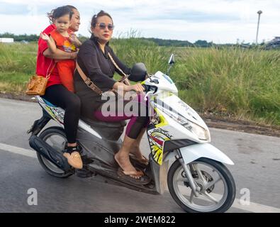 SAMUT SAKHON, THAILANDIA, DEC 03 2023, le donne guidano una moto con un bambino piccolo Foto Stock