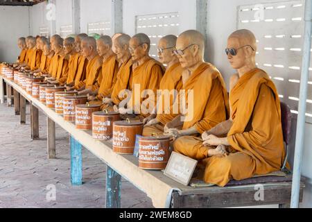 SAMUT SAKHON, THAILANDIA, DEC 03 2023, Una fila di statue di cera di monaci buddisti seduti in un tempio buddista Foto Stock