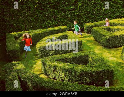 I bambini in esecuzione nel giardino labirinto Foto Stock