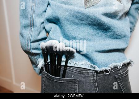 Spazzole per il trucco inserite nella tasca posteriore di eleganti jeans Foto Stock