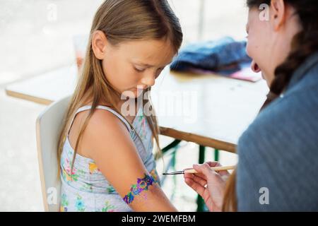 Bambina che ottiene il tatuaggio glitterato alla festa di compleanno Foto Stock