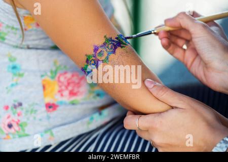 Bambina che ottiene il tatuaggio glitterato alla festa di compleanno Foto Stock