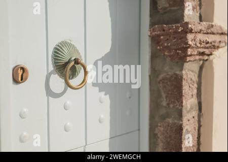Esclusivo battito in ottone su una porta blu chiaro alla luce del sole Foto Stock