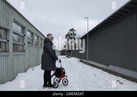 donna in pensione che cammina felicemente nella neve con il suo rollator Foto Stock