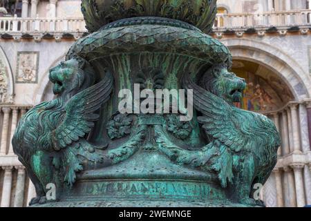 Antico ornamento di strada con leoni alati e basilica di San Marco sullo sfondo, in San Piazza Marco, famosa attrazione turistica a Venezia, Italia. Foto Stock