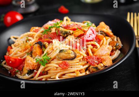 Classici spaghetti alla marinara con cozze e salmone su tavola scura. Spaghetti con salsa marinara. Foto Stock