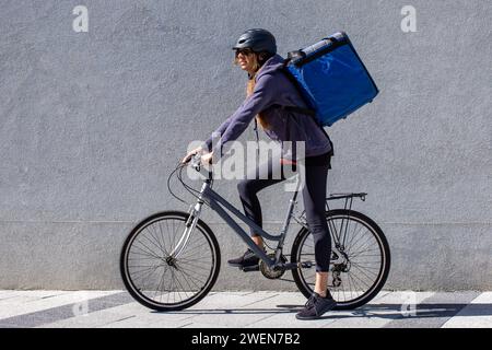 donna in bicicletta che consegna ordine in città Foto Stock