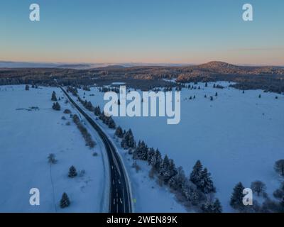 Vista aerea di una strada innevata tra alberi sempreverdi Foto Stock