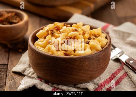 Maccheroni e formaggio con pezzi di pancetta in una ciotola di legno su un palude e un tavolo rustico in legno Foto Stock