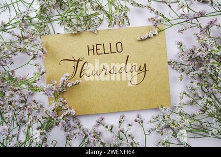 Ciao giovedì scritto su carta con decorazione a cornice di fiori su sfondo rosa Foto Stock