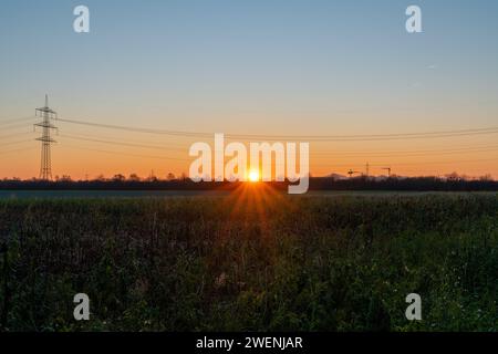 Sonnenaufgang über Feld mit Strommast Foto Stock