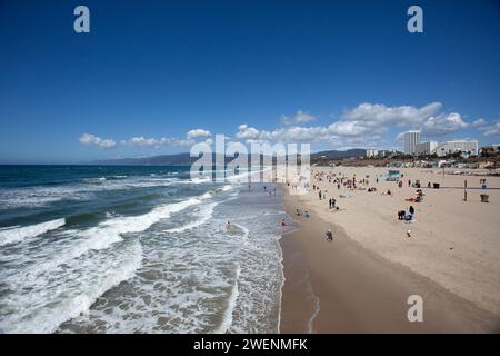 Ampia ripresa della spiaggia di Santa Monica dal molo di Santa Monica con onde che si infrangono e gente che si diverte sulla spiaggia sabbiosa. Foto Stock