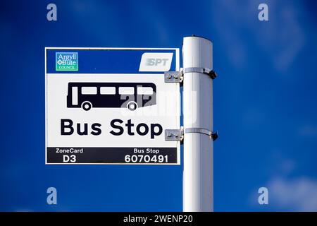 Primo piano isolato di un segnale di fermata dell'autobus per SPT con l'icona di un pullman, con ID fermata e numeri di percorso del servizio visibili contro un cielo blu Foto Stock