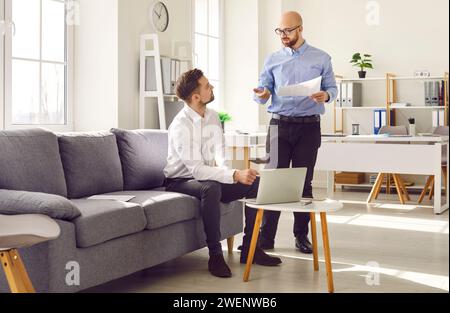 Due uomini d'affari che discutono del loro progetto durante la riunione in ufficio Foto Stock