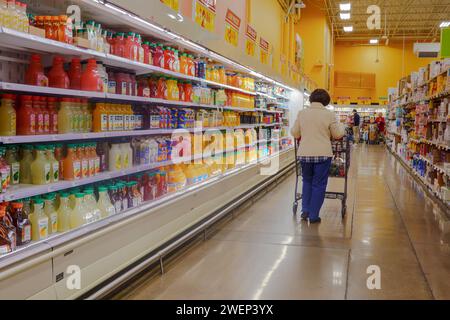 Donne anziane con carrello che camminano accanto al negozio di alimentari, frigorifero pieno di vari succhi di frutta Foto Stock