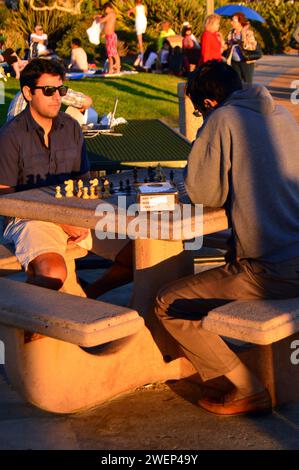 Due amici si divertono a una partita di scacchi a un tavolo all'aperto in un parco vicino alla riva di Laguna Beach, California Foto Stock